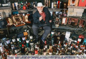 Daley sitting down surrounded by his whiskey collection 