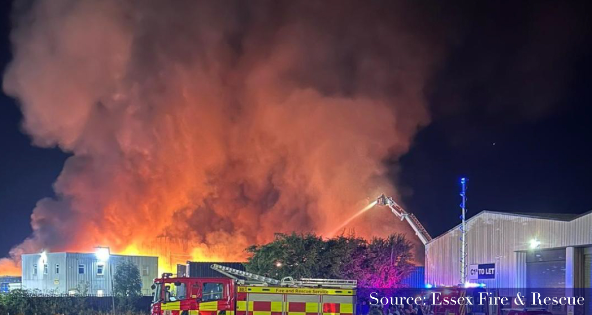 large fire at night lighting sky, with fire crew standing by